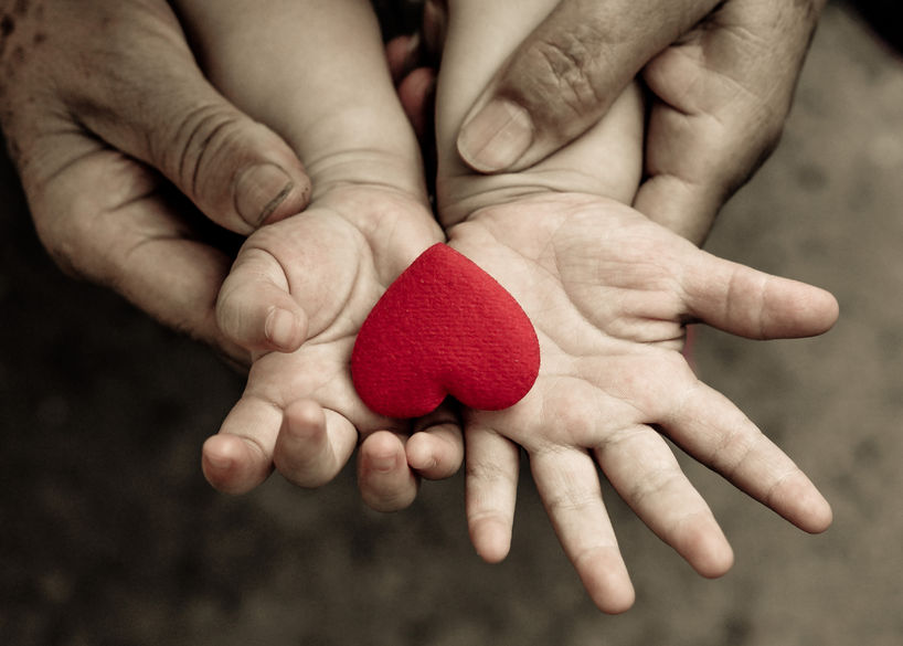 43771768 - old hands holding young hand of a baby with red heart