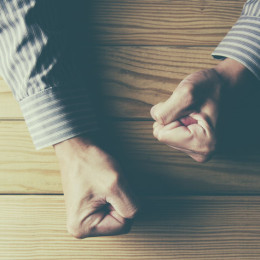 55511936 - man fists clenched on a wooden table in anger