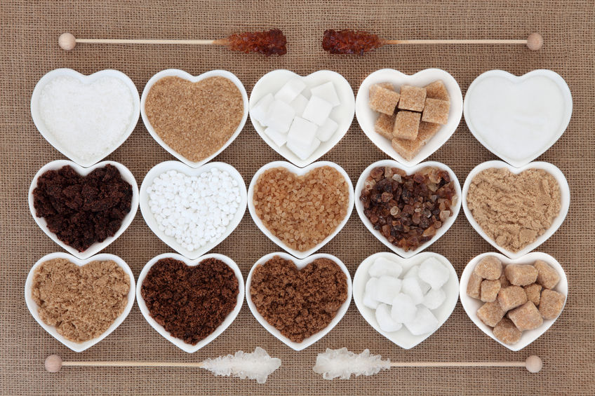 35089428 - white and brown sugar selection in heart shaped bowls with crystal lollipop sticks over hessian background.